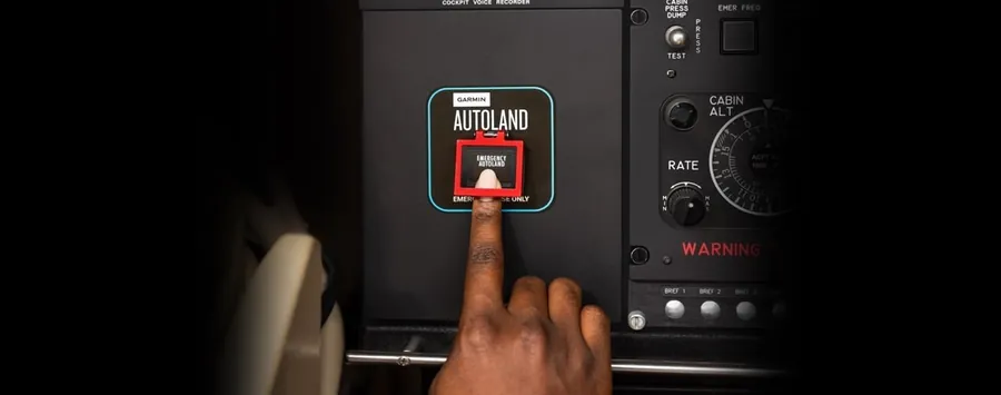 A finger presses the red Garmin Autoland button in an aircraft cockpit