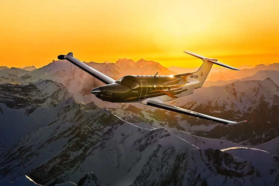 Pilatus PC-12 PRO in flight above snow-covered mountains at sunset, one of the aircraft with Garmin Autoland